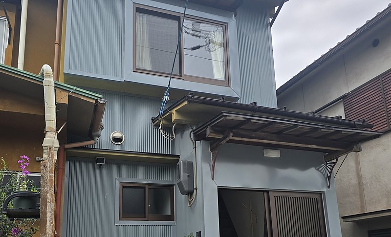 The front of Kichi Otsu, a two-storey house with grey-blue cladding and a tiled roof