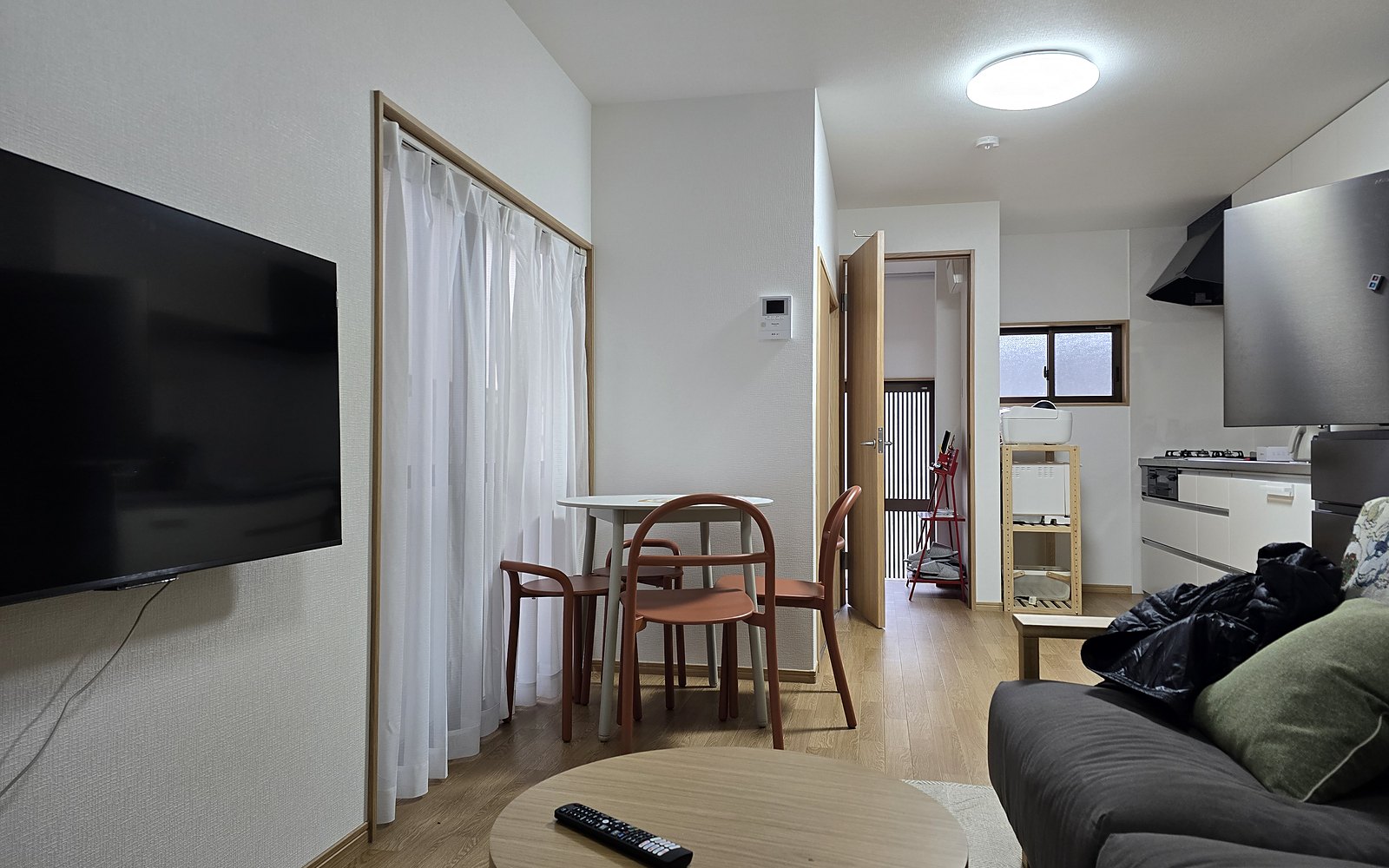 The living and dining room at Kichi Otsu, white walls, wood floor and an open kitchen beyond